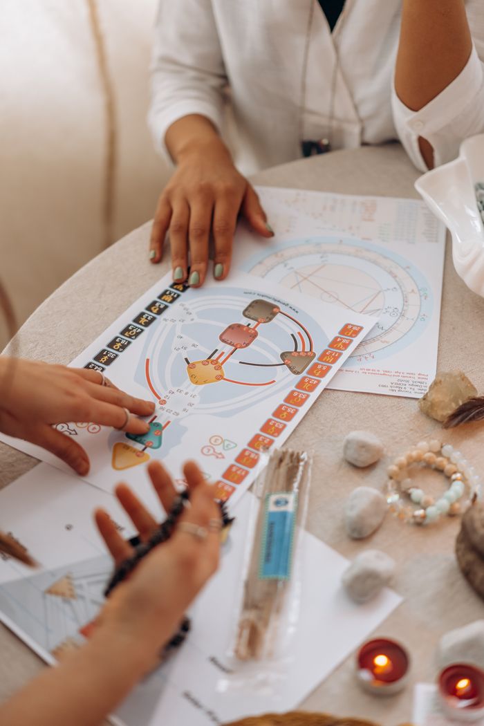 A serene scene of astrology chart reading with crystals, candles, and hands in focus.